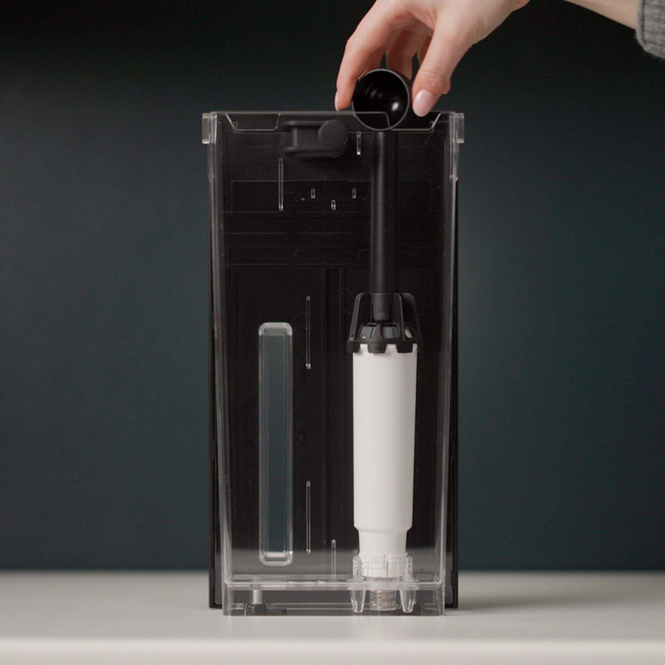 Eine Hand setzt eine schwarze Kappe in einen transparenten Wassertank ein.
