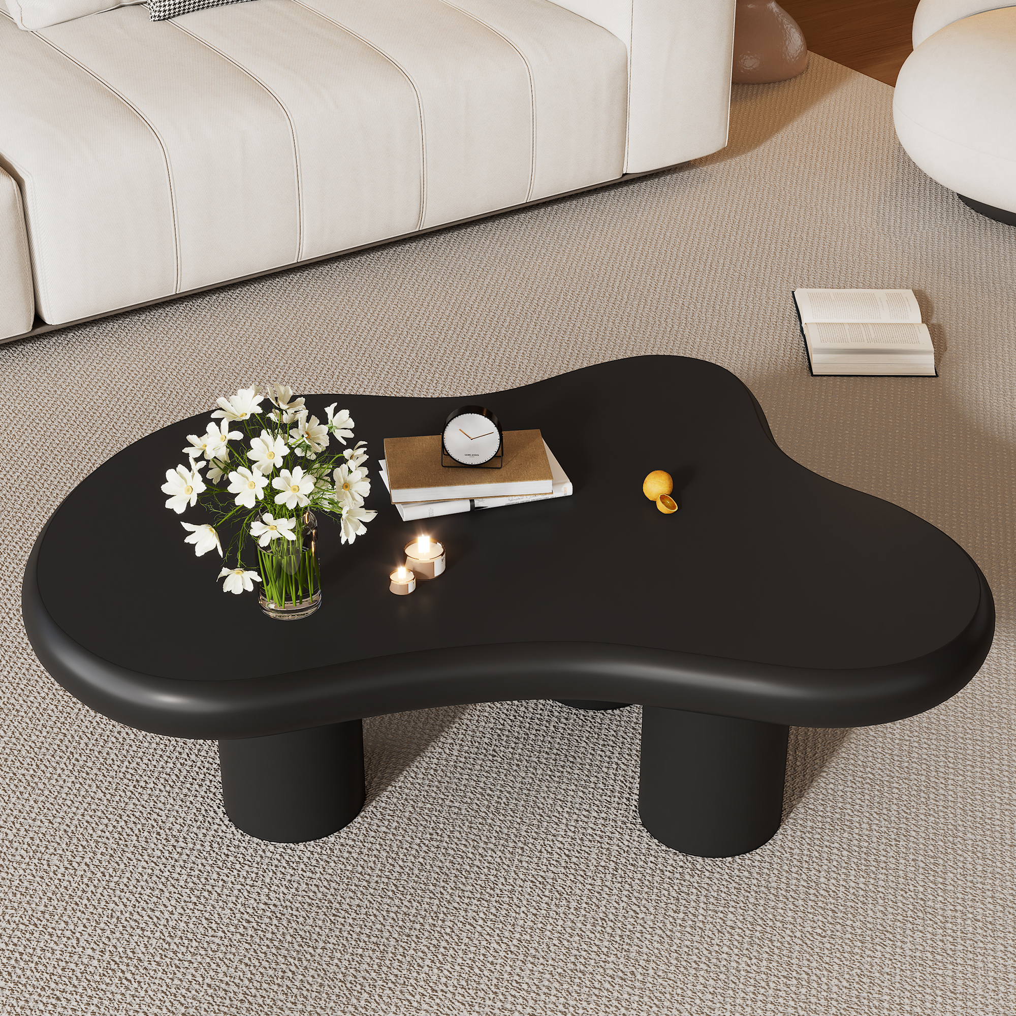 Ein schwarzer Couchtisch mit Blumen, Büchern, Kerzen und Zitrone auf einem Teppich.
