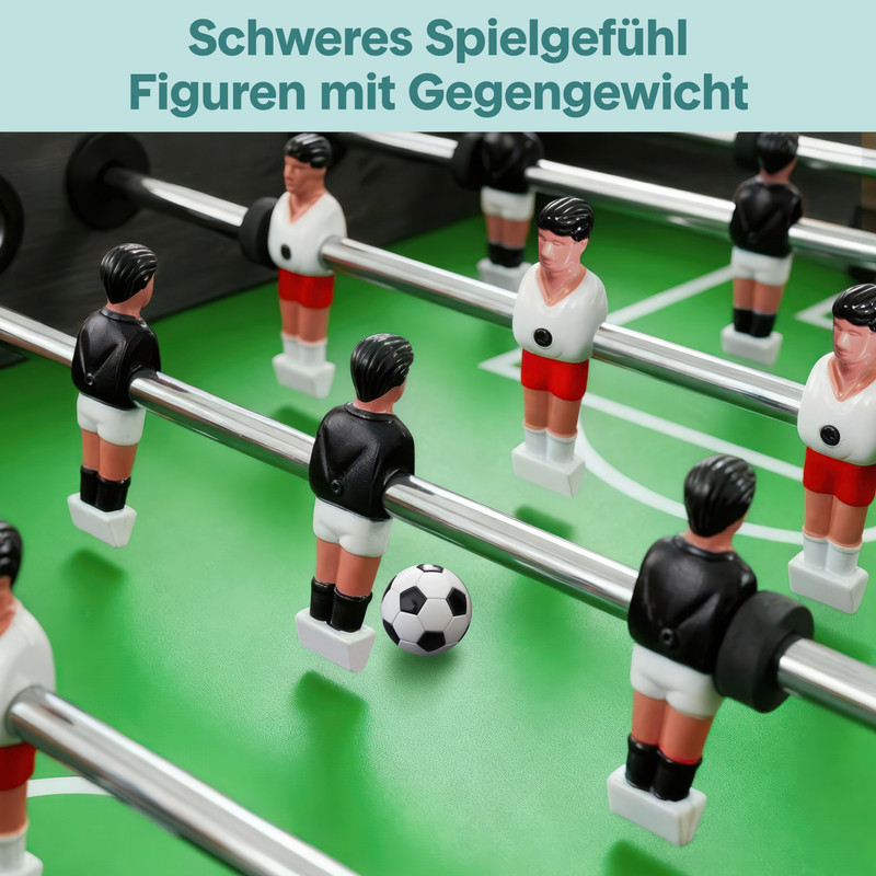 Tischfußballfiguren in Schwarz und Weiß stehen auf einem grünen Feld mit einem Ball.