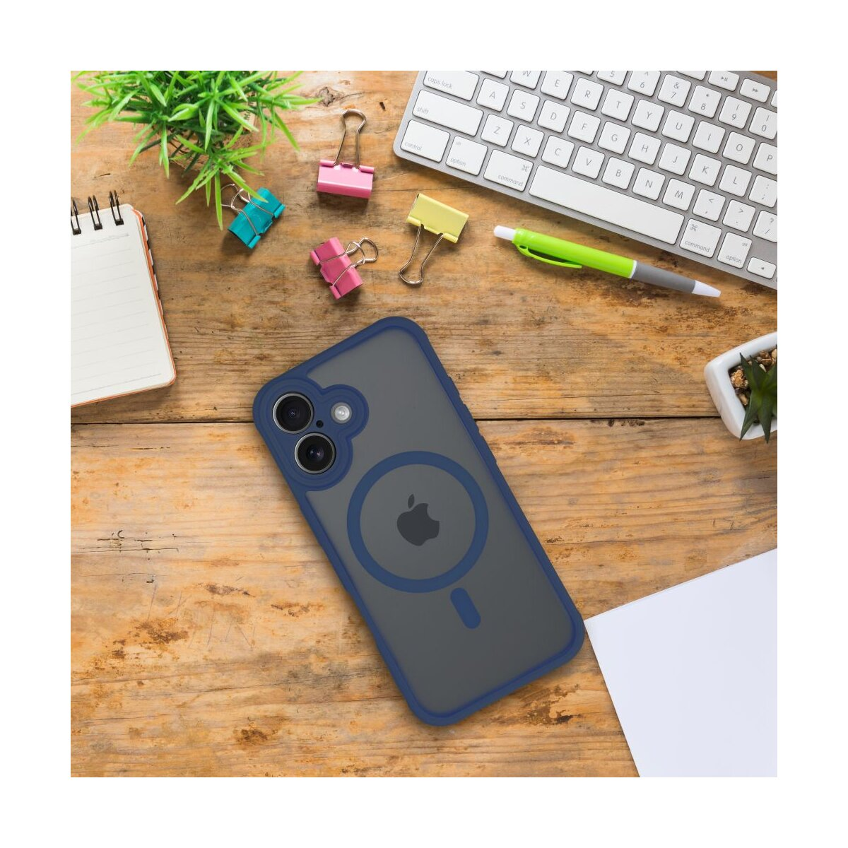 Ein iPhone mit Hülle liegt auf einem Holztisch neben einer Tastatur und Büromaterial.