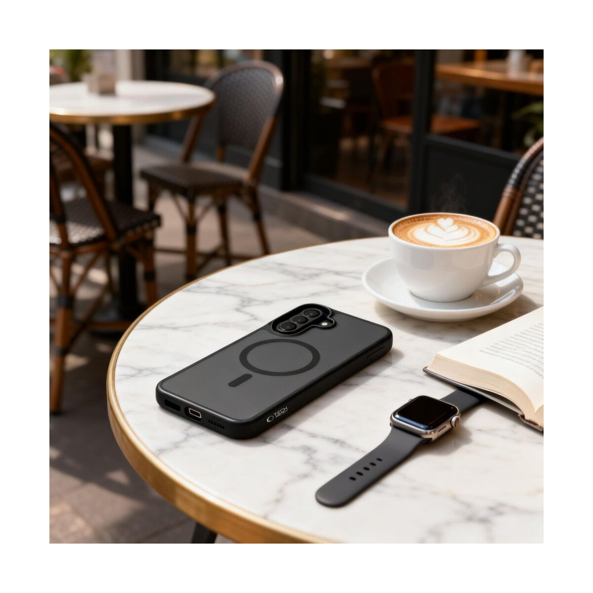 Schwarzes Handyhülle, Kaffeetasse mit Latte Art, Smartwatch und Buch auf Marmortisch.