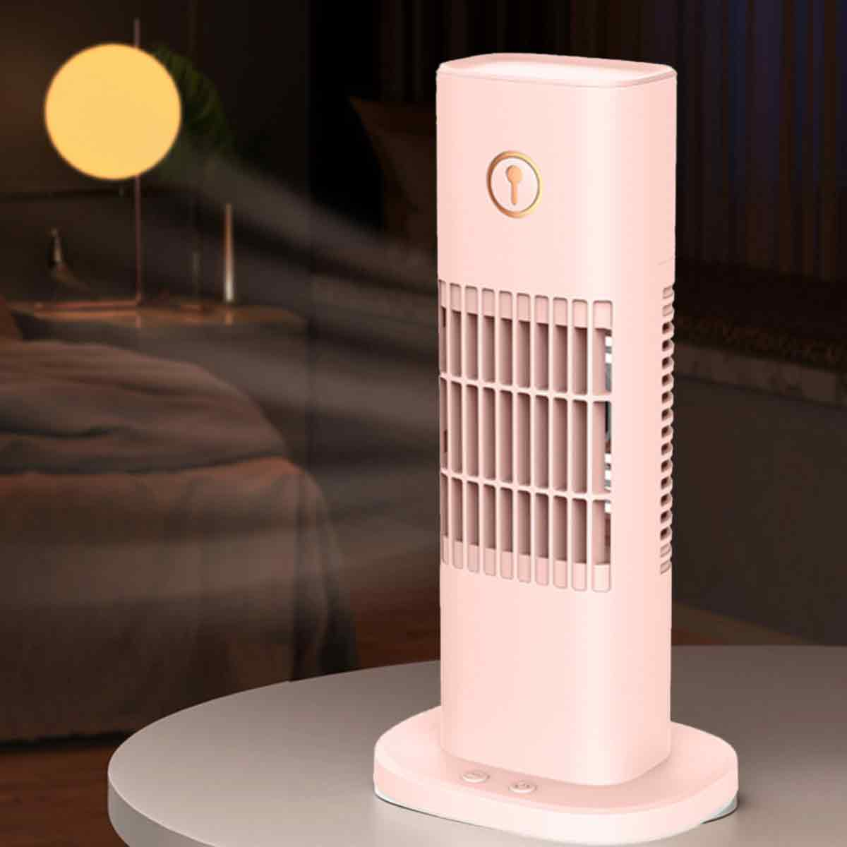 Ein rosafarbener Turmventilator steht auf einem Tisch, im Hintergrund ein Nachttisch mit Lampe.