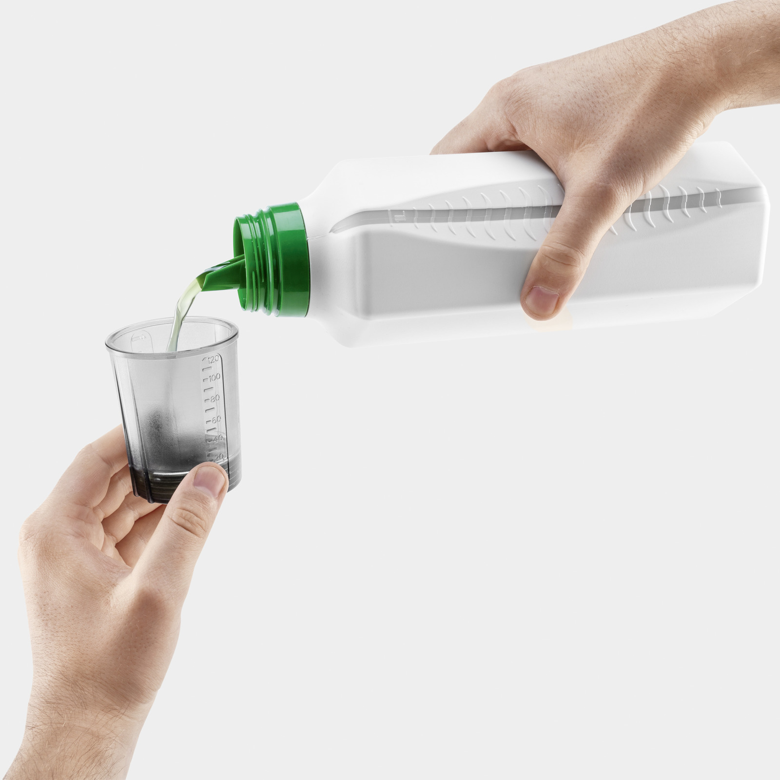 Flüssigkeit wird aus weißer Flasche mit grünem Deckel in Messbecher gegossen.