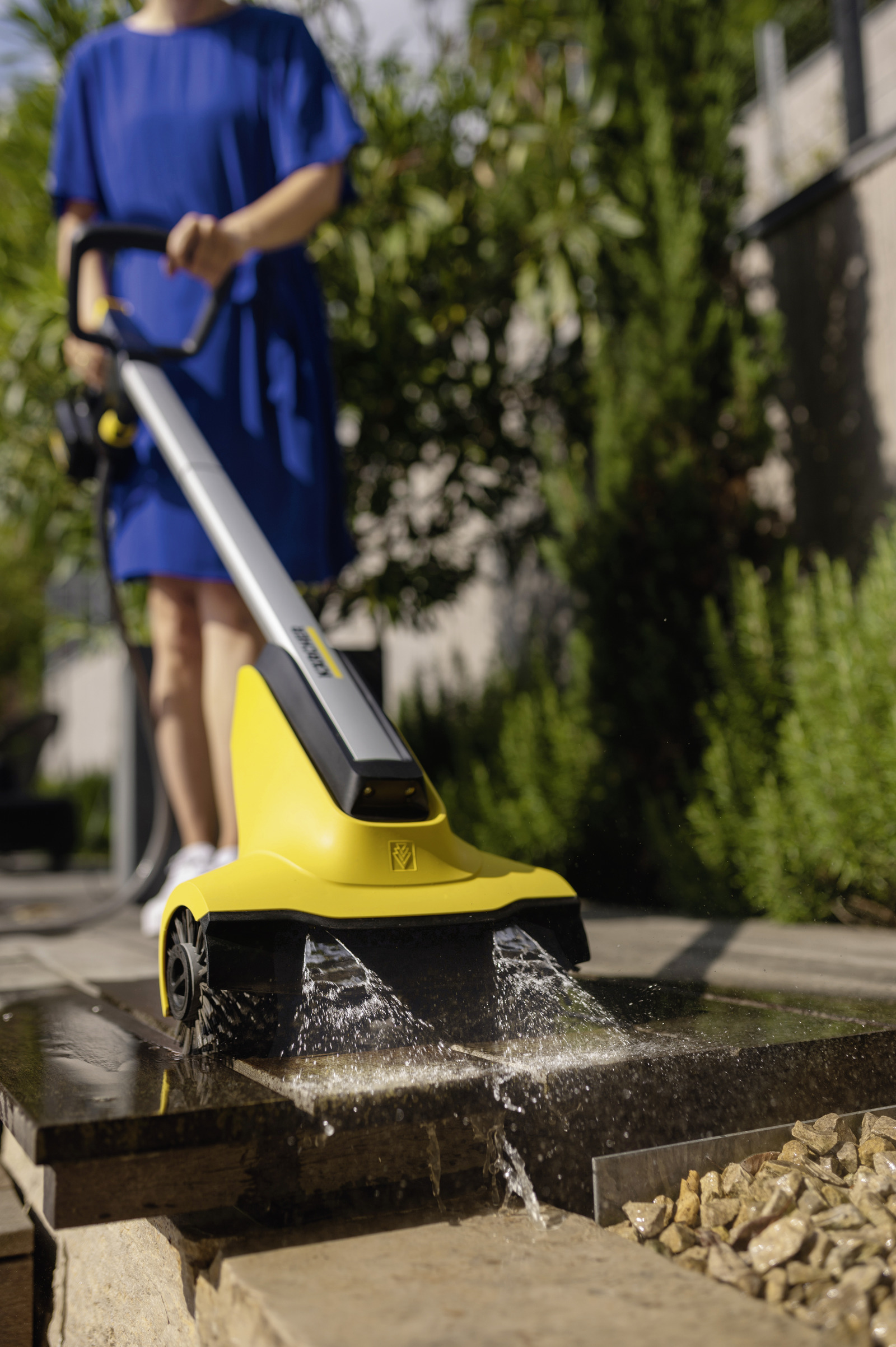 Ein Mann reinigt Steine mit einem gelben Gerät, das Wasser sprüht.