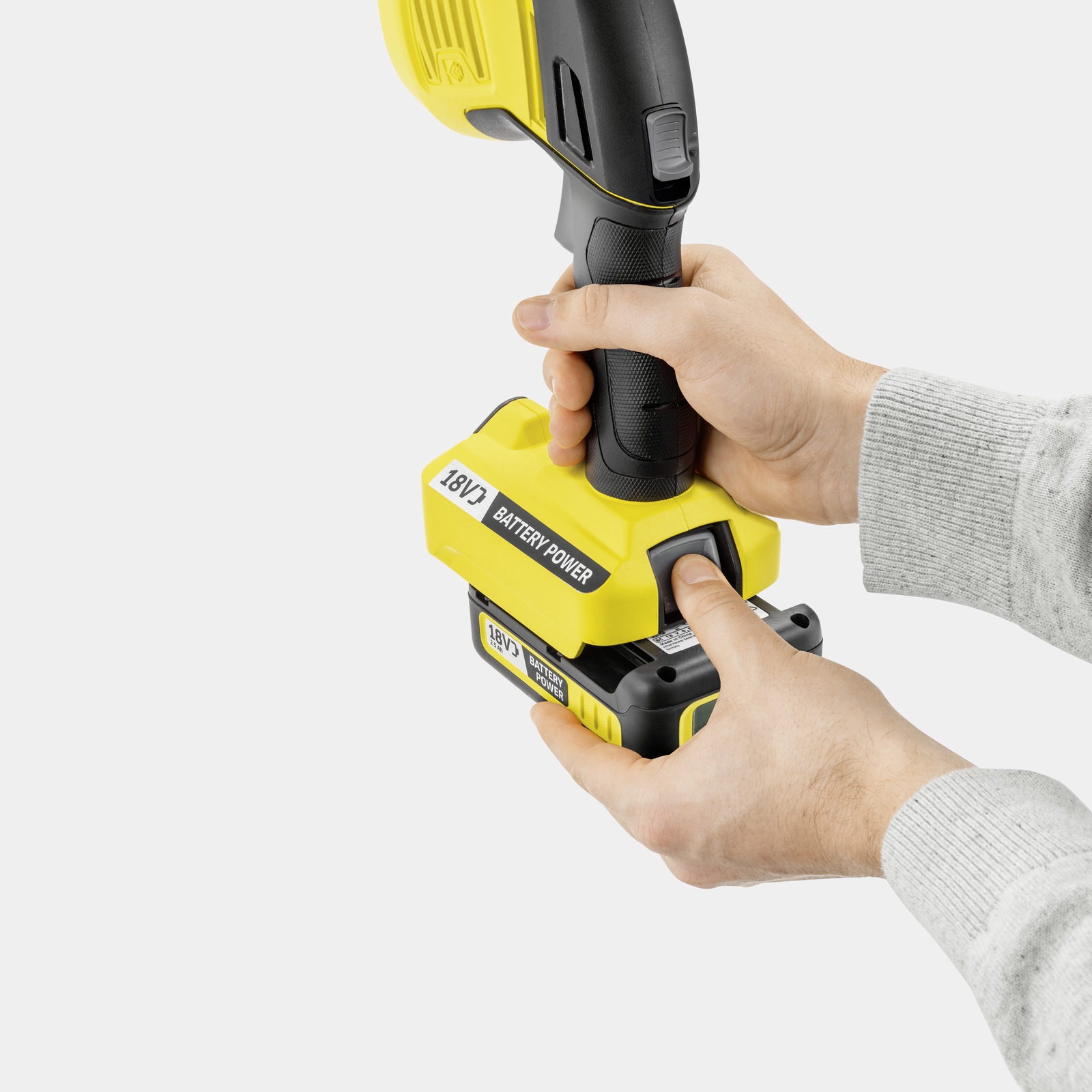 Manos insertando una batería amarilla de 18V en una herramienta.