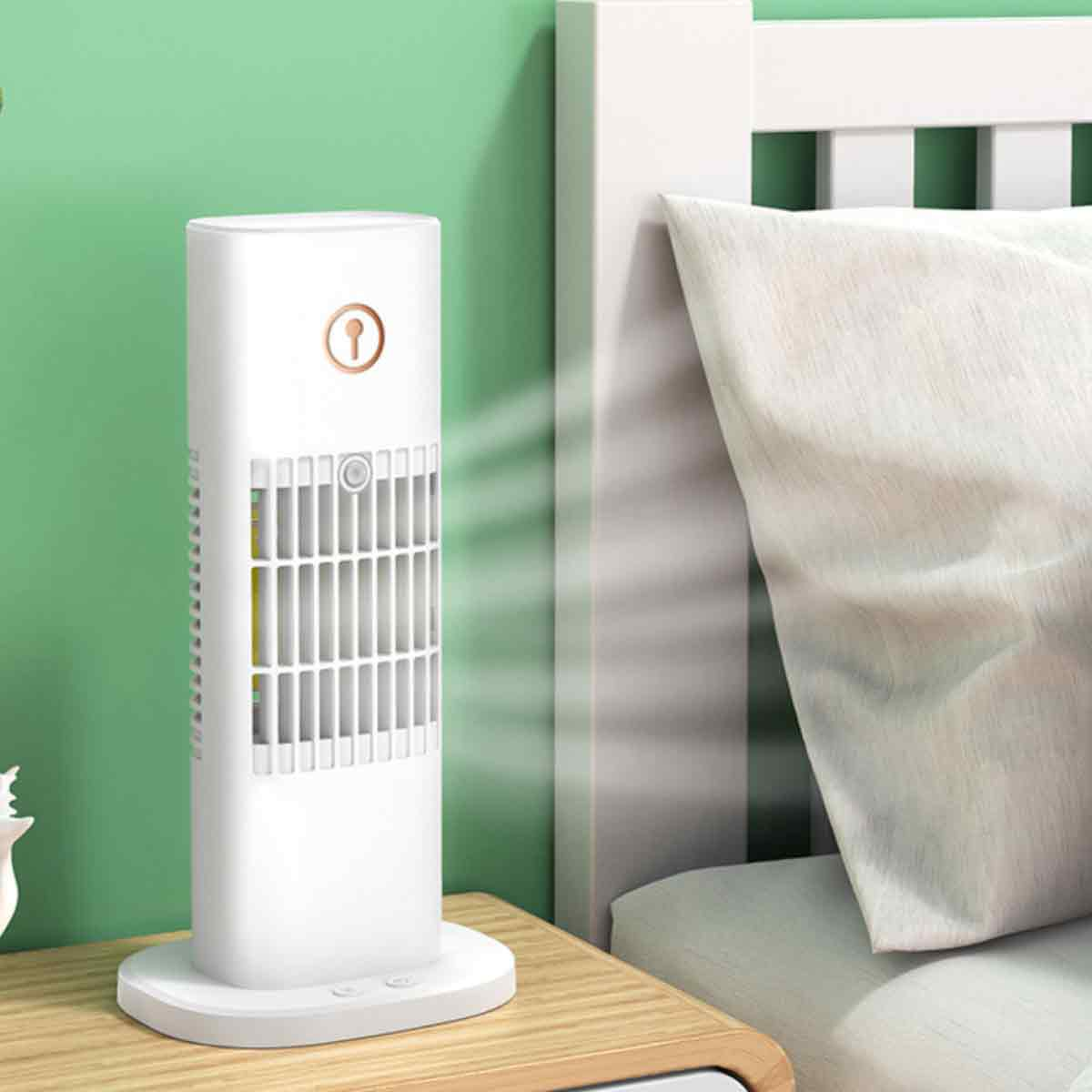 Ein weißer Turmventilator steht auf einem Nachttisch neben einem Bett mit weißer Bettwäsche.