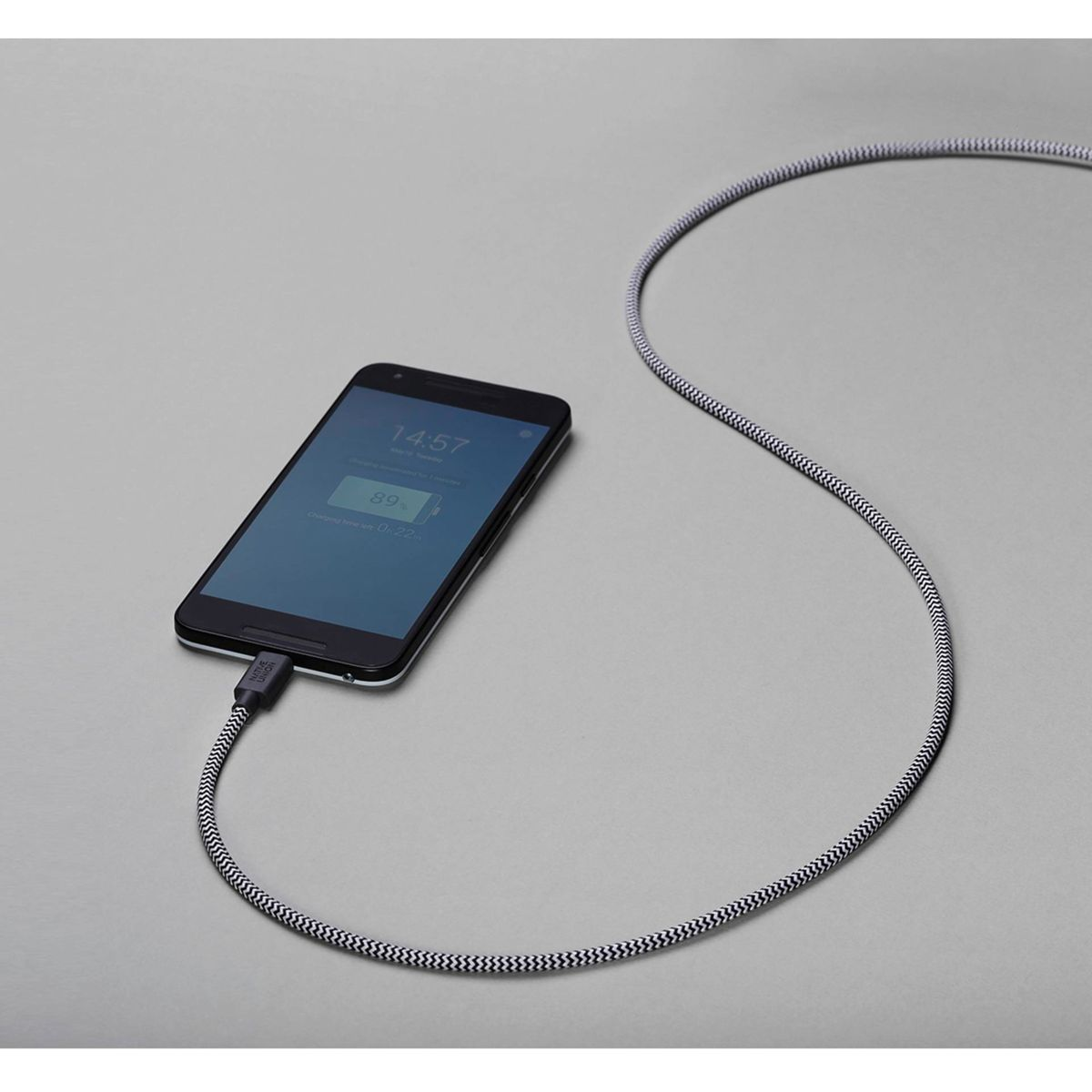 Ein Smartphone wird mit einem schwarz-weißen Kabel aufgeladen. Der Bildschirm zeigt 89% Akku.