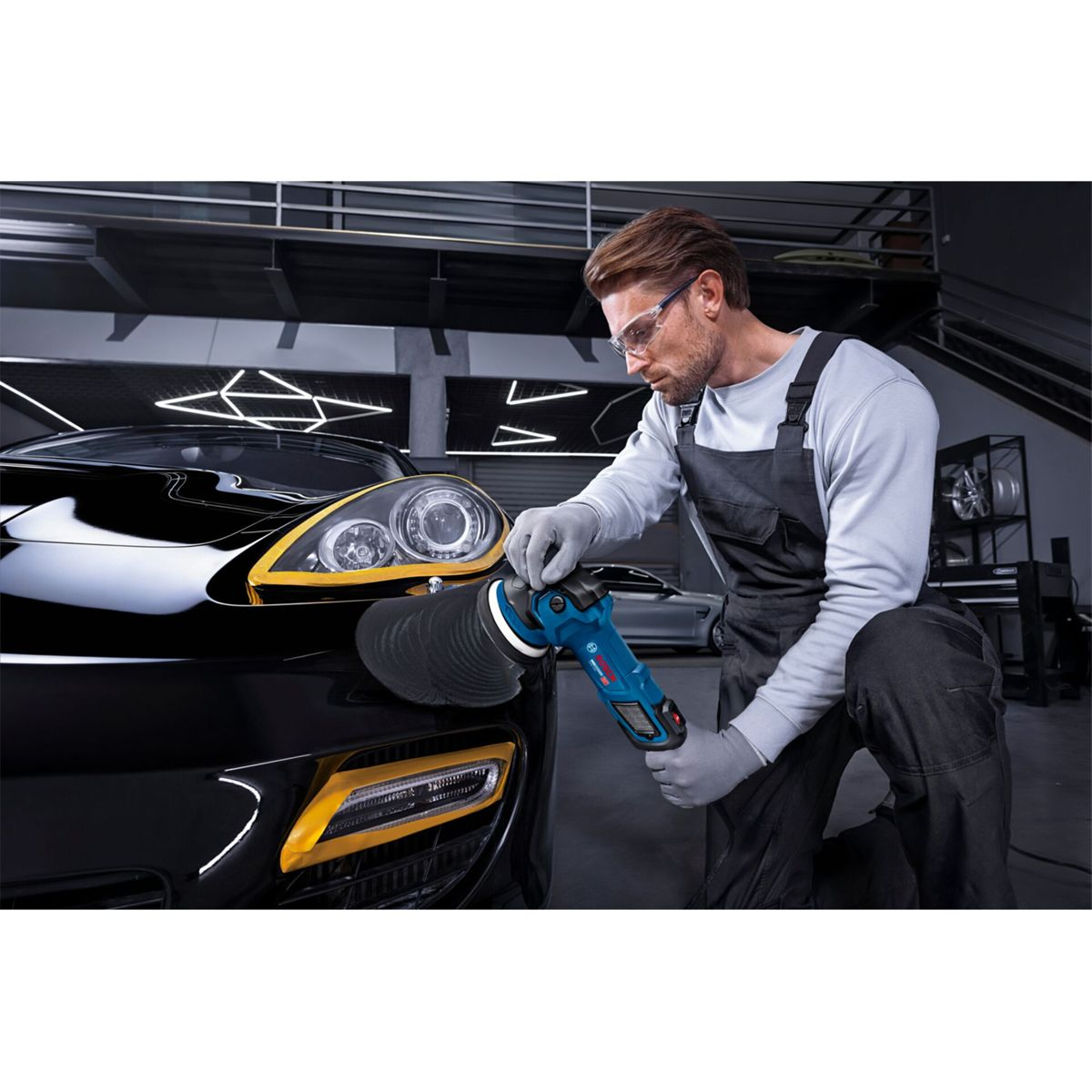 Mann poliert schwarzes Auto mit Poliermaschine im Detail.