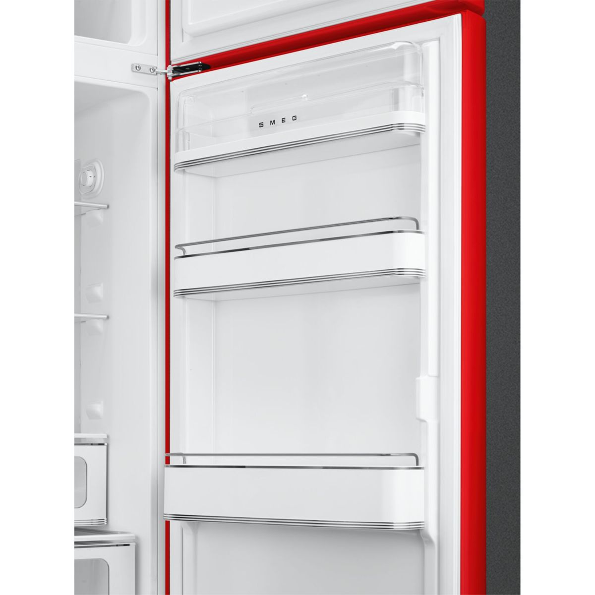 Interior de un refrigerador SMEG rojo con estantes blancos y cajón transparente.