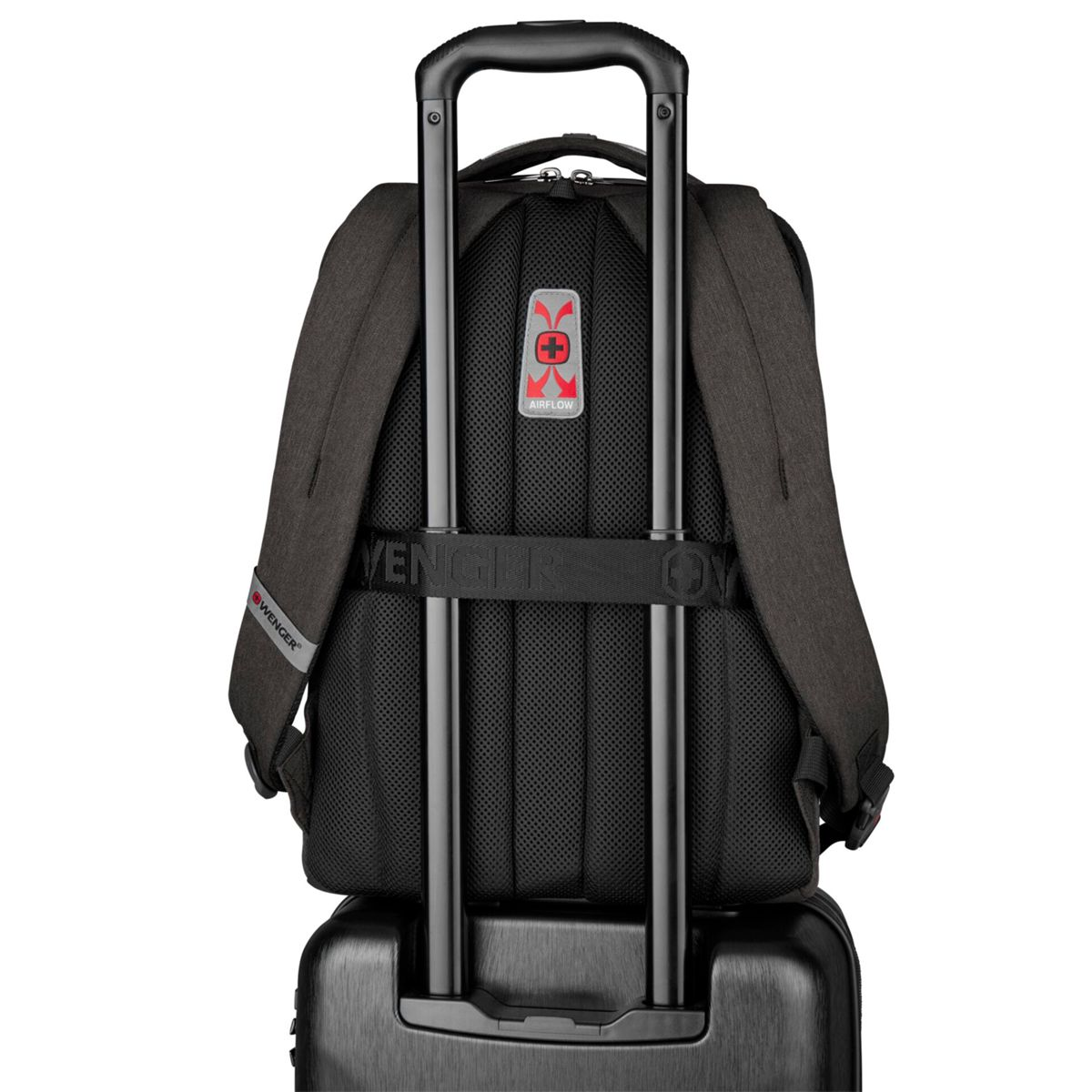 Ein dunkler Rucksack mit Netzrücken, der auf einem Koffer sitzt.