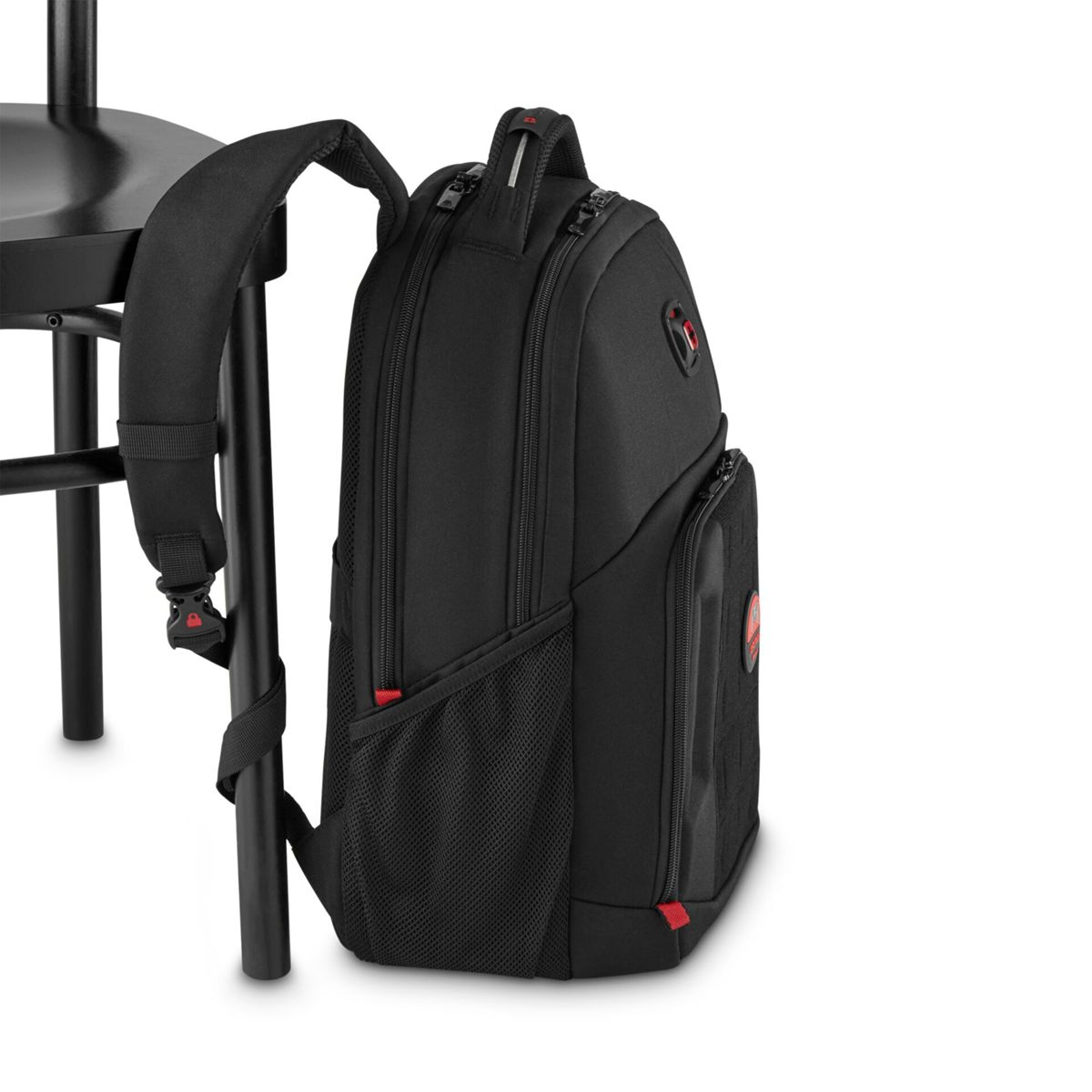 Zaino nero con accenti rossi appoggiato a una sedia nera.