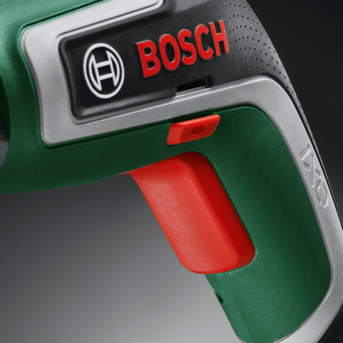 Nahaufnahme eines grünen Bosch IXO Schraubers mit rotem Griff und Schalter.