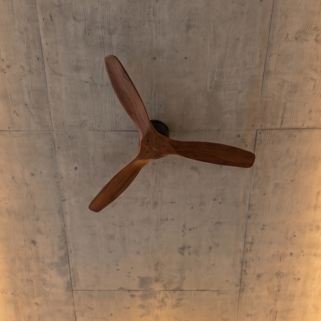 Un ventilador de techo de madera de tres aspas cuelga de una pared de hormigón.