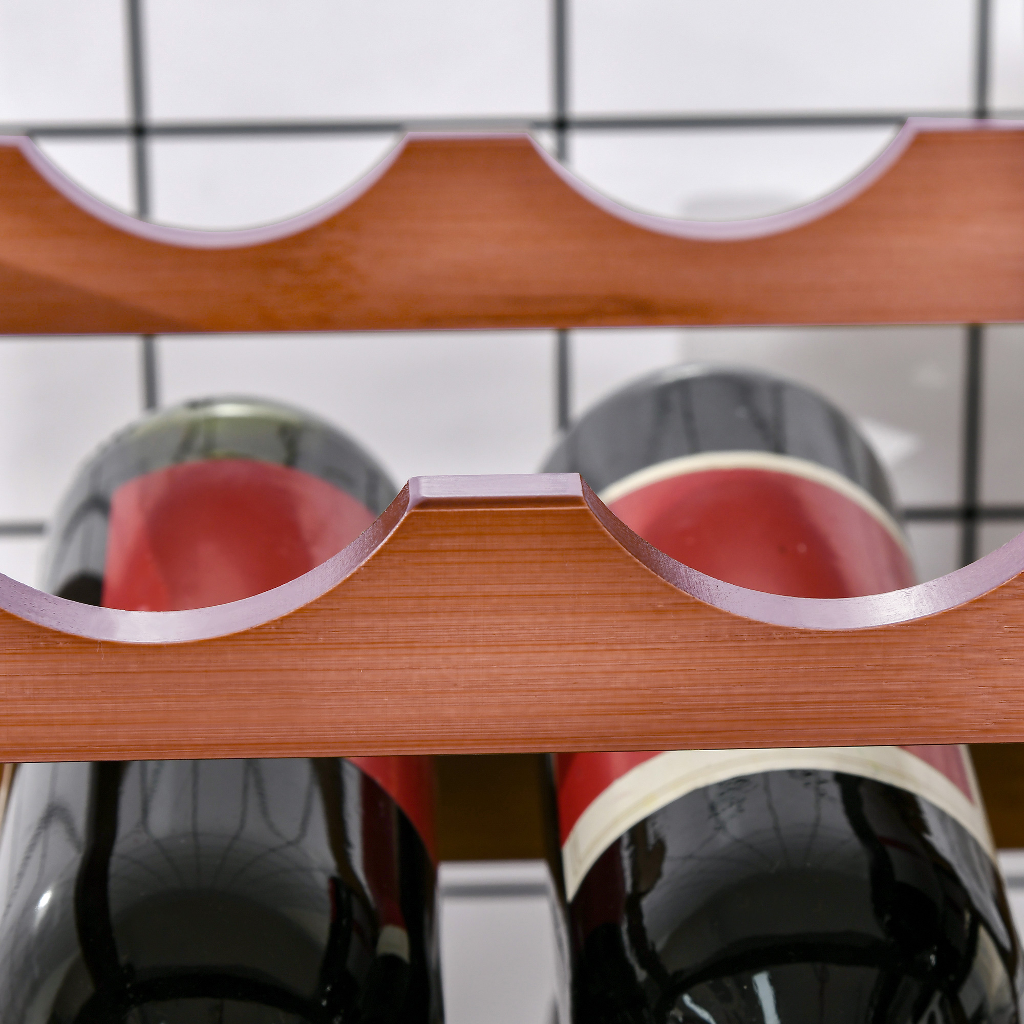 Primer plano de un botellero de madera marrón que sostiene dos botellas de vino oscuras con etiquetas rojas sobre un fondo de azulejos blancos.