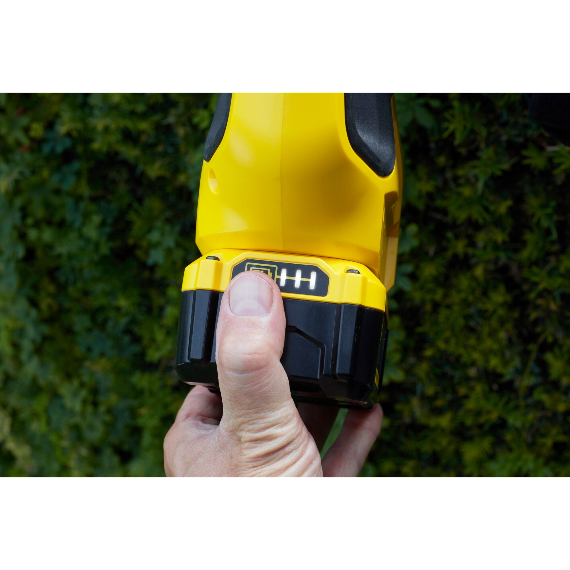 Una mano tiene un elettroutensile giallo con batteria nera e indicatore di carica.