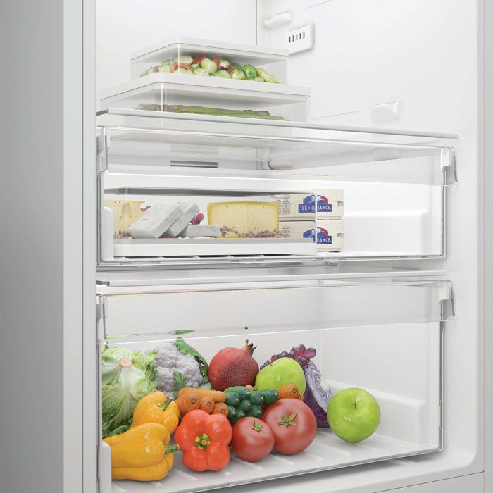 Szuflady lodówki wypełnione świeżymi produktami: warzywa, ser i owoce.