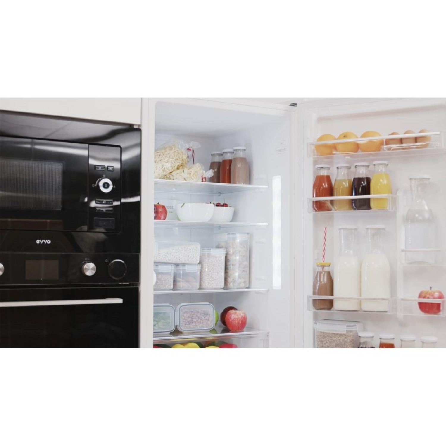 Refrigerador abierto con comida: manzanas, botellas de jugo, leche y recipientes de granos.