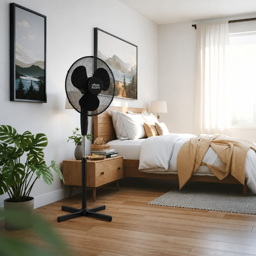 Un ventilador de pie negro se encuentra frente a una cama de madera con ropa blanca y un tiro amarillo.