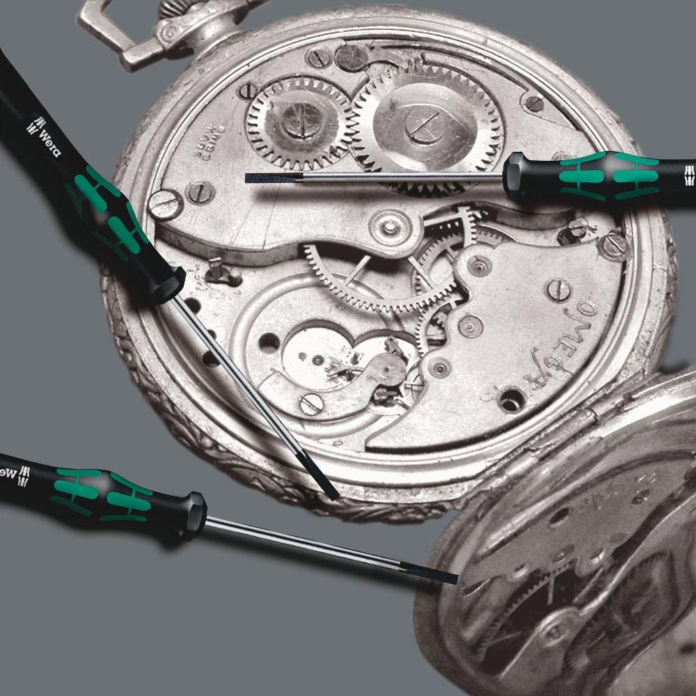 Cacciaviti di precisione lavorano su un vecchio meccanismo di orologio.