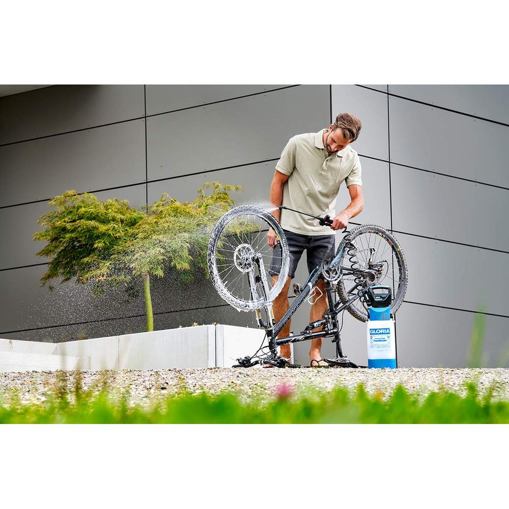 Un uomo lava la sua bicicletta con un'idropulitrice davanti a un edificio.