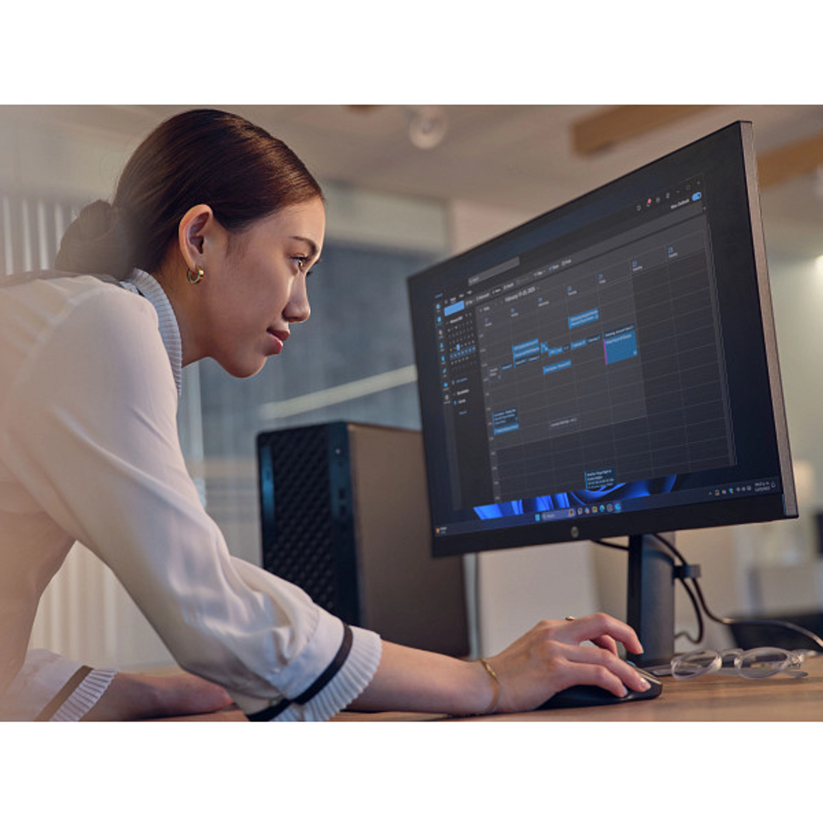 Donna alla scrivania usa il computer con calendario sullo schermo.