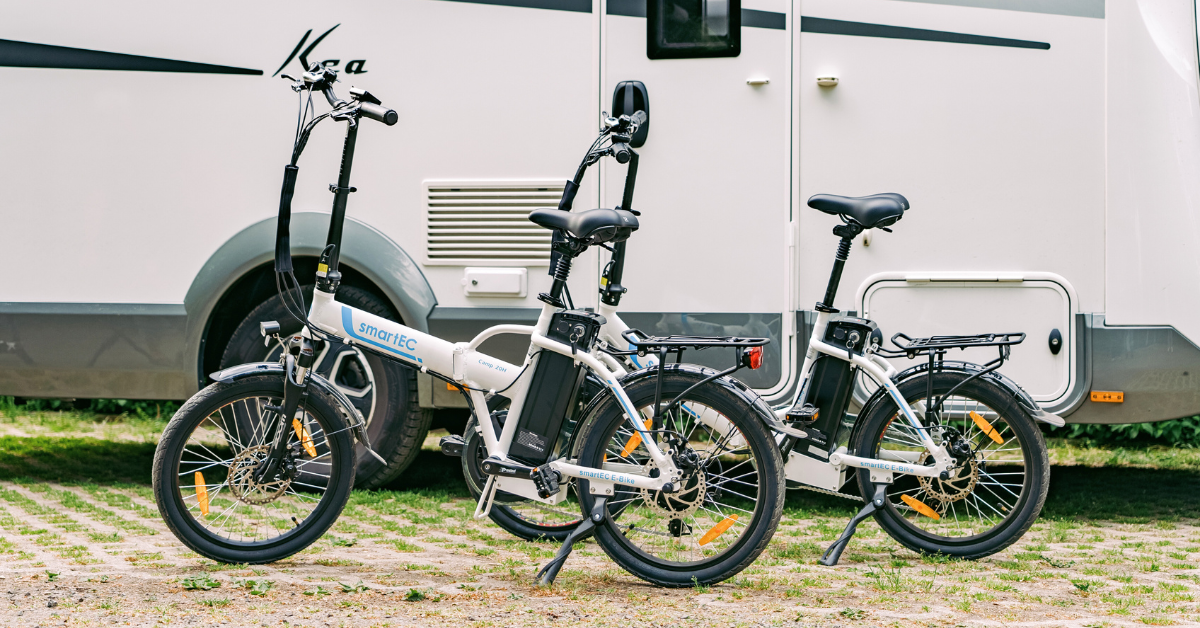 Zwei weiße E-Bikes stehen vor einem Wohnmobil auf einem gepflasterten Untergrund.