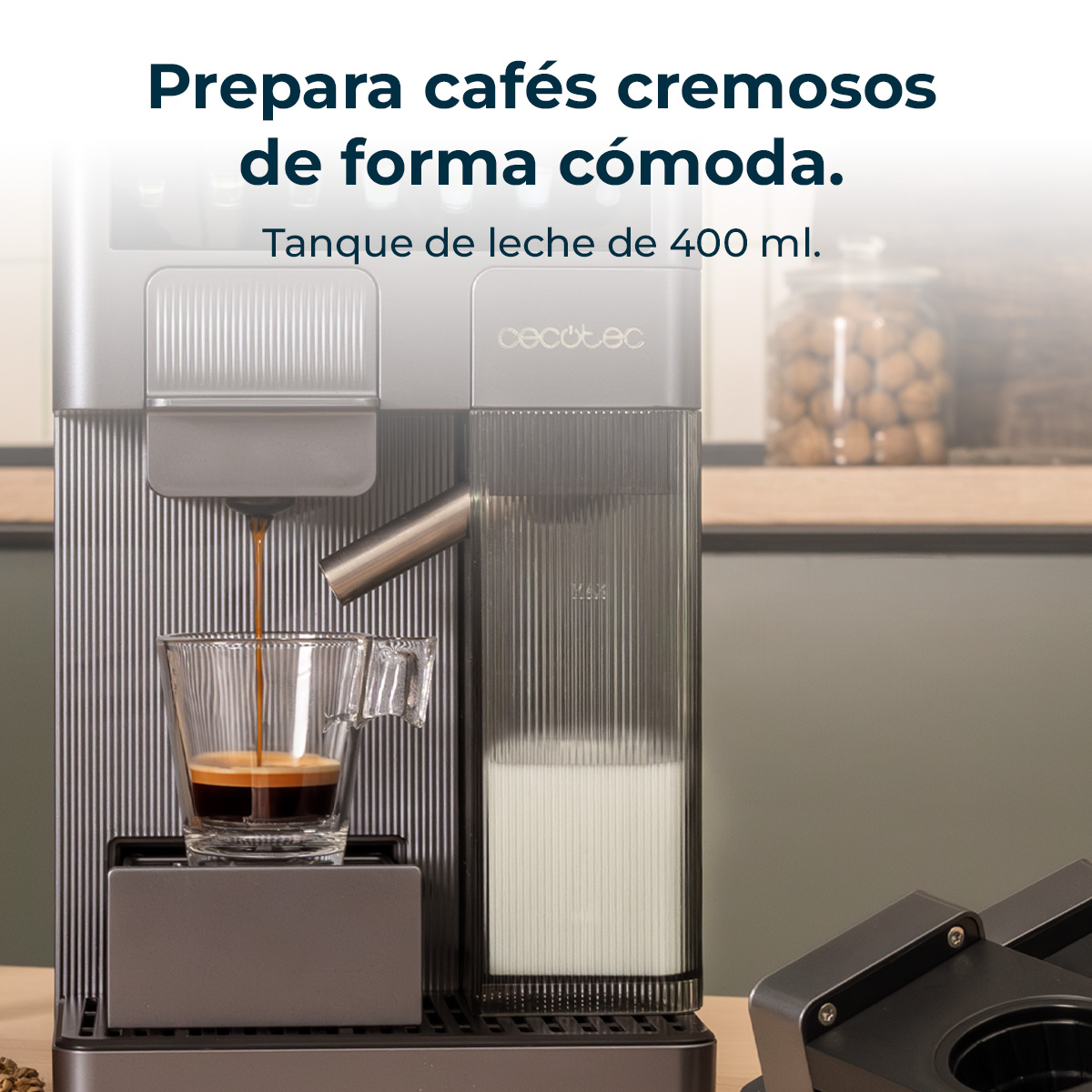 Una cafetera prepara espresso en una taza de cristal. Depósito de leche al lado.