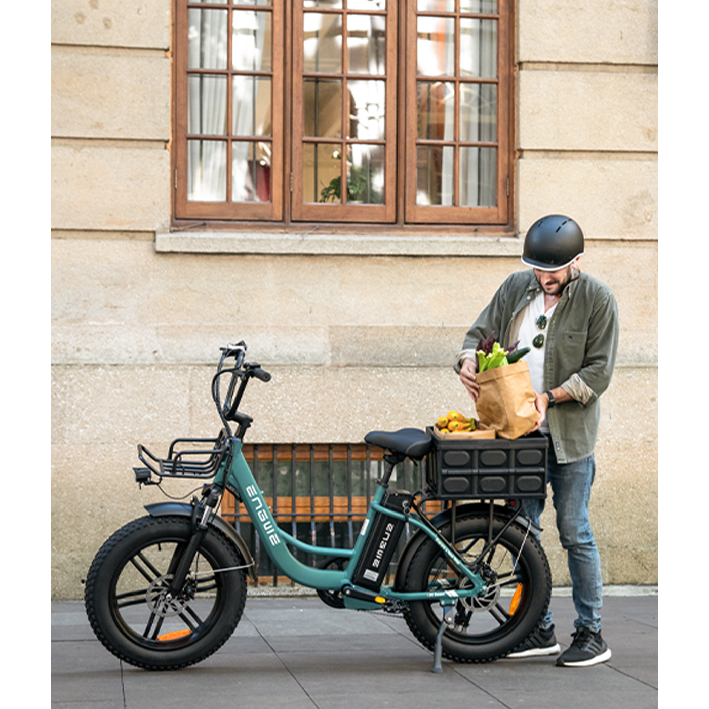 Ein Mann mit Helm packt Lebensmittel aus einer Papiertüte in einen Korb auf einem Elektrofahrrad.