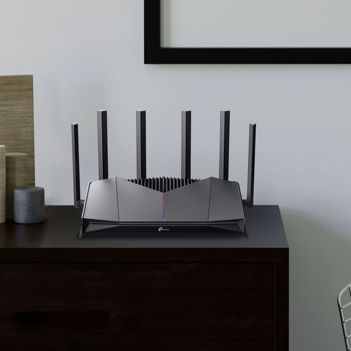 Un router scuro con sei antenne è seduto su una cassettiera scura.
