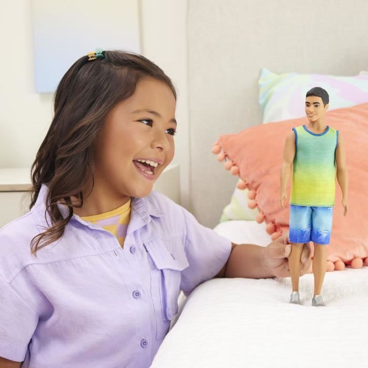 Een lachend meisje speelt met een Ken-pop op een bed.
