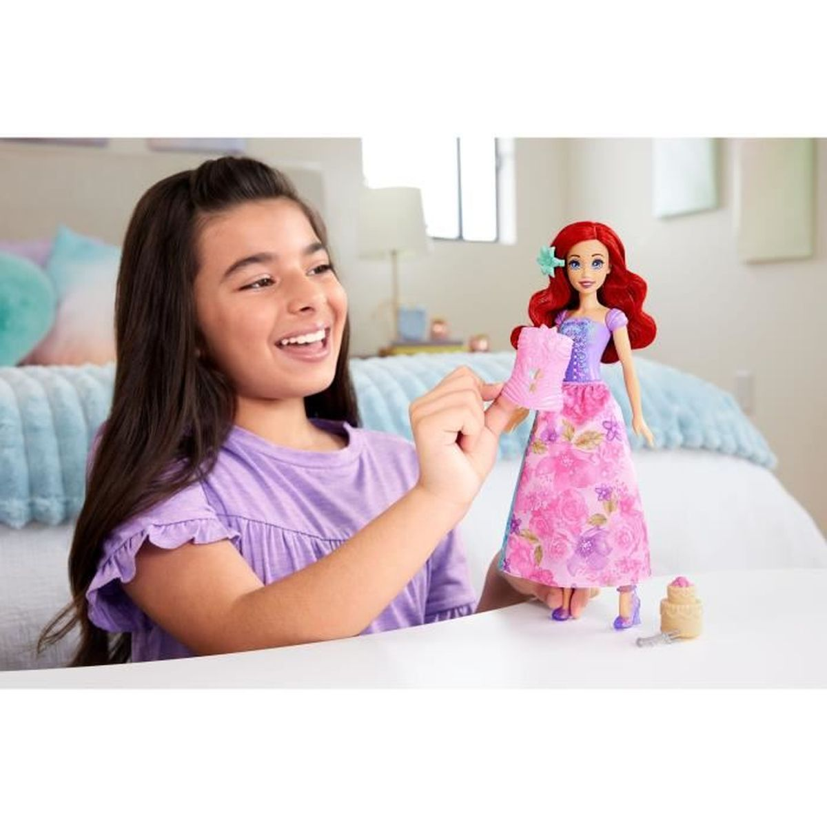 Ein Mädchen mit einem lila T-Shirt spielt mit einer Ariel-Puppe in einem rosa Kleid.