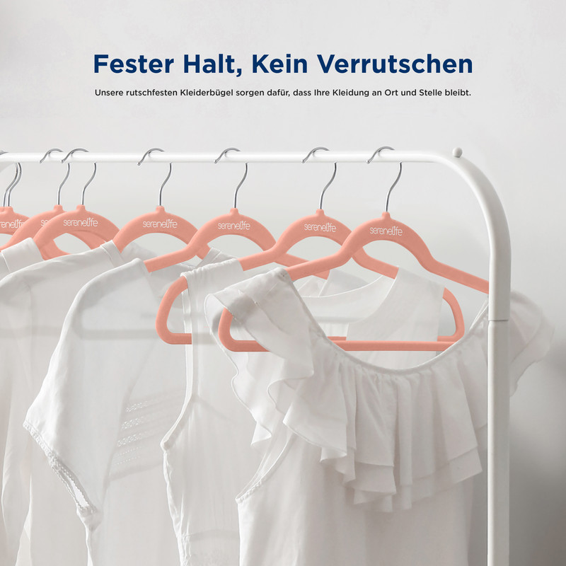 Mehrere weiße Kleidungsstücke hängen an rosa Kleiderbügeln an einer Garderobe.