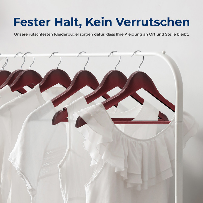 Mehrere weiße Kleidungsstücke hängen an dunklen Holzbügeln an einer Garderobe.