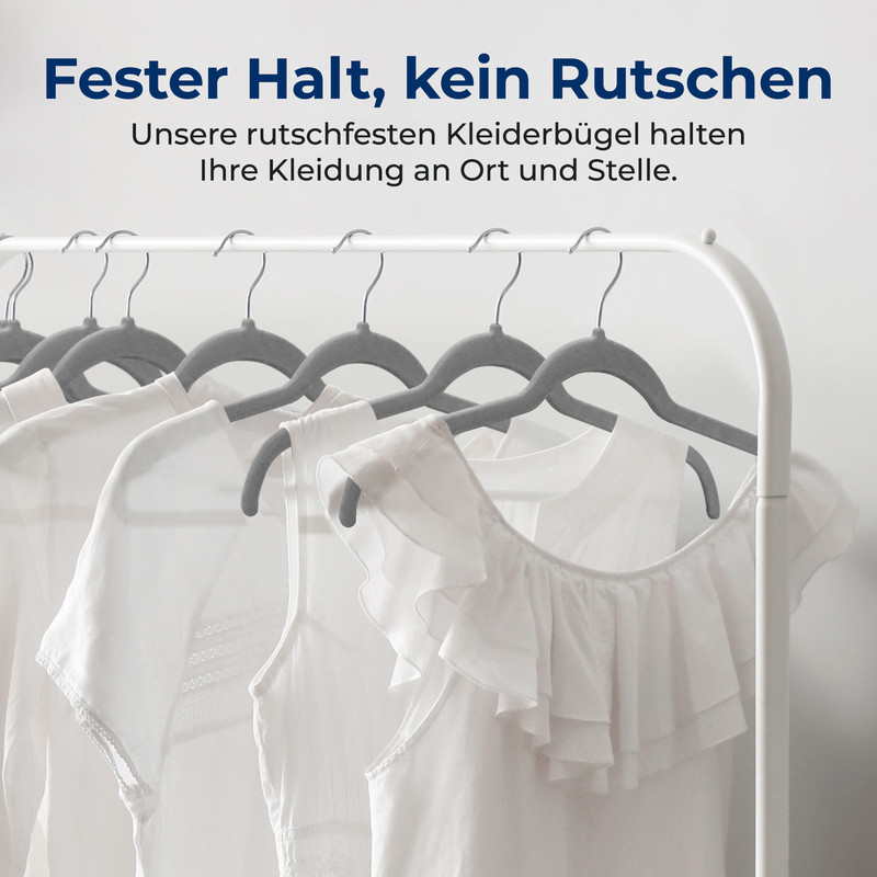 Weiße Kleider auf grauen Samtbügeln an einer Kleiderstange.