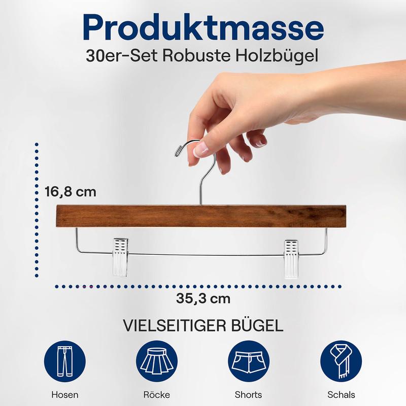 Eine Hand hält einen Holzbügel mit Metallklammern, Maße 16,8 cm mal 35,3 cm, für diverse Kleidung.