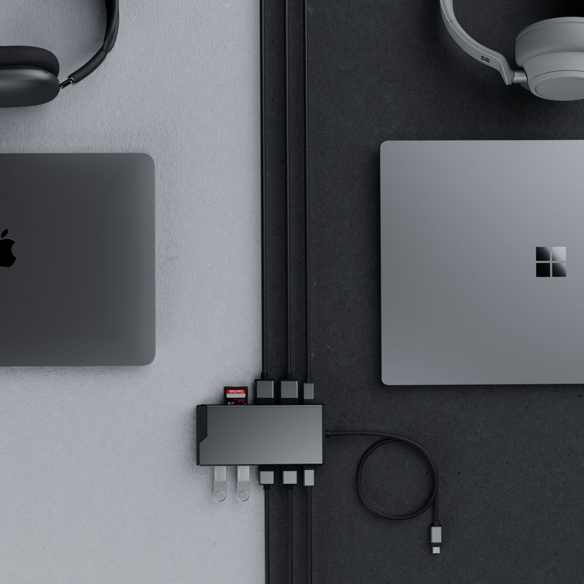 Deux ordinateurs portables, des écouteurs et un hub USB-C avec carte SD sur fond gris et noir.