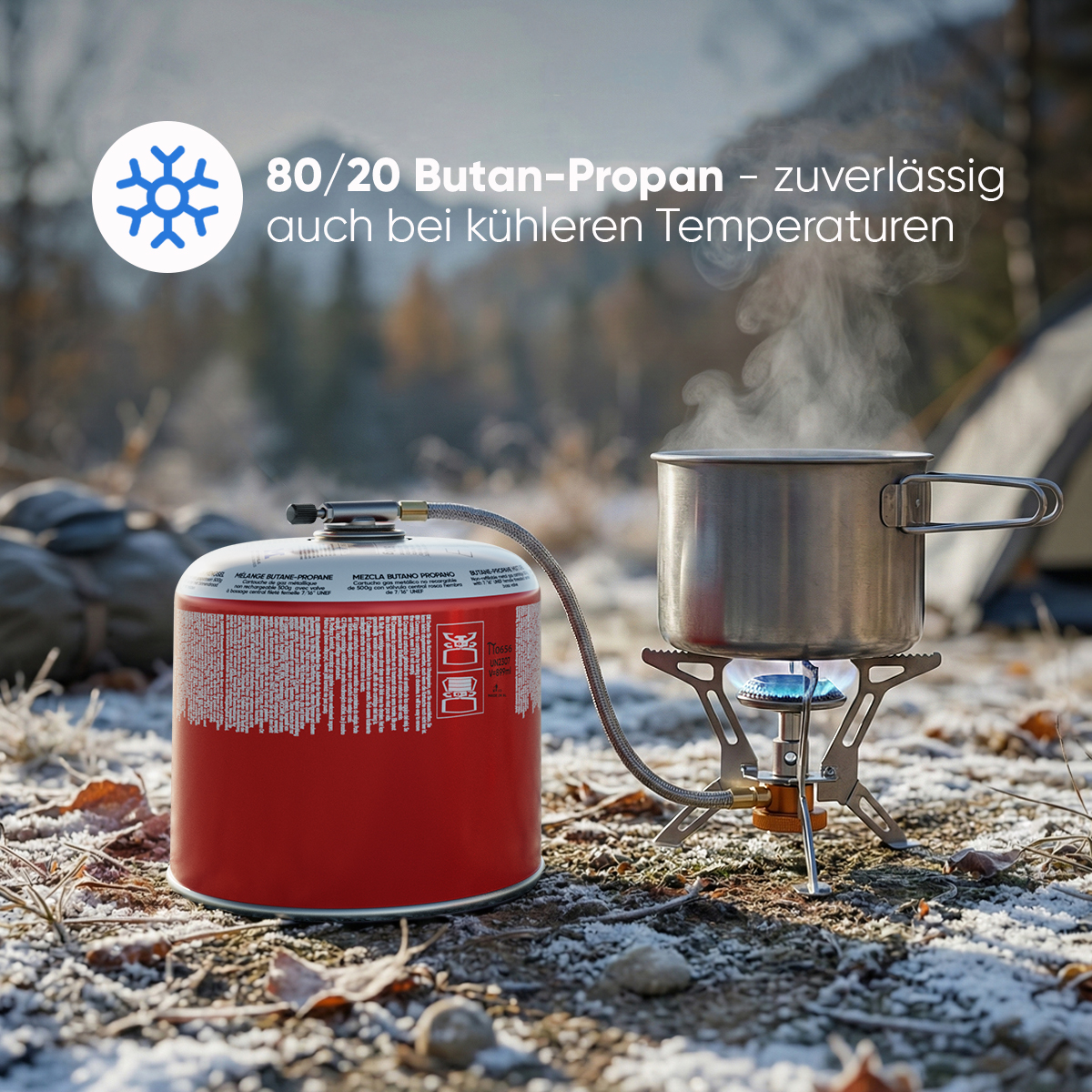 Ein roter Gaskocher mit Topf auf einem Campingkocher in einer verschneiten Landschaft.