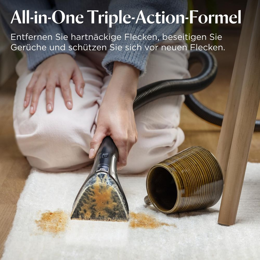 Ein Reinigungsgerät saugt Flecken von einem Teppich, neben einer umgekippten Tasse.