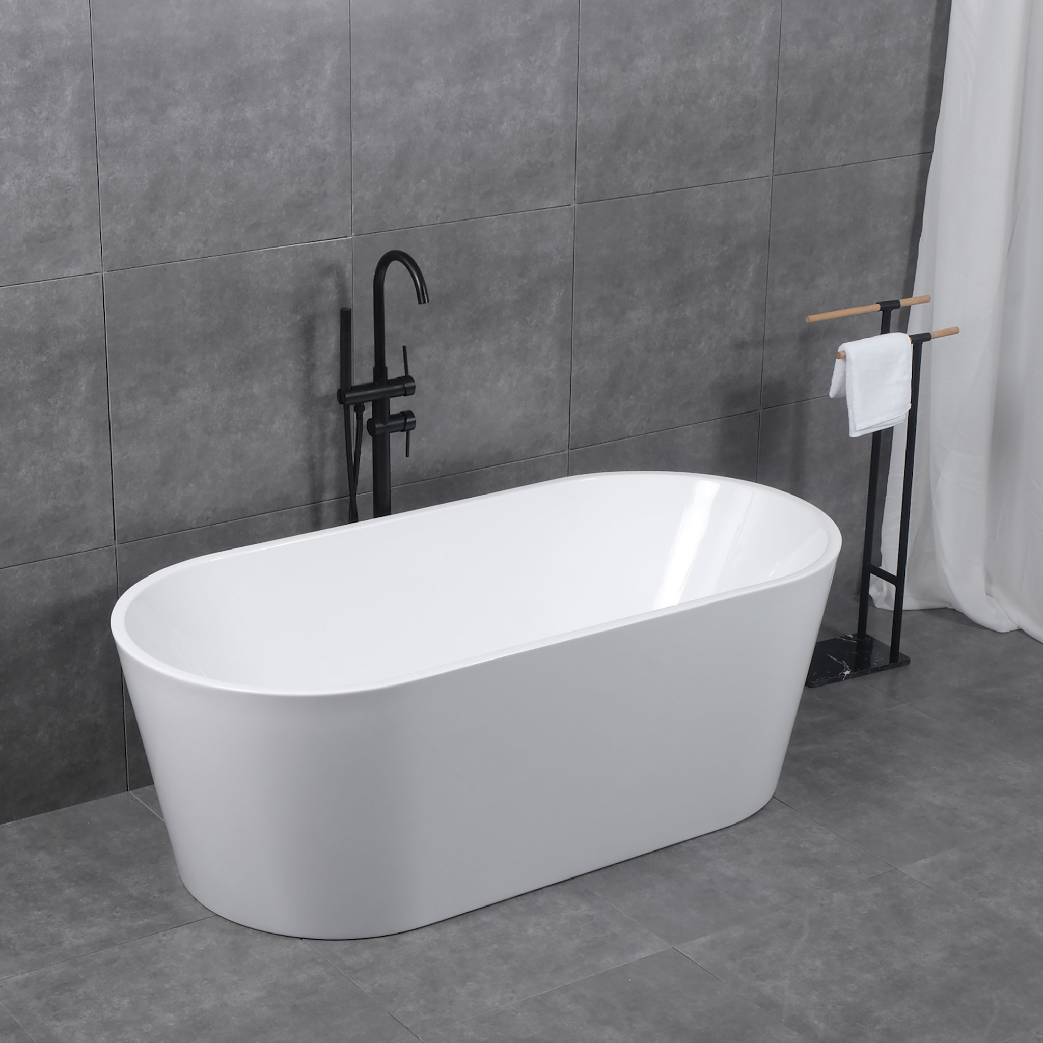 Freistehende weiße Badewanne mit schwarzer Armatur auf grau gefliestem Boden.