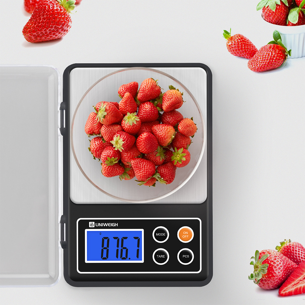 Eine digitale Küchenwaage mit einer Schüssel voller Erdbeeren und einer Anzeige von 876,7 g.
