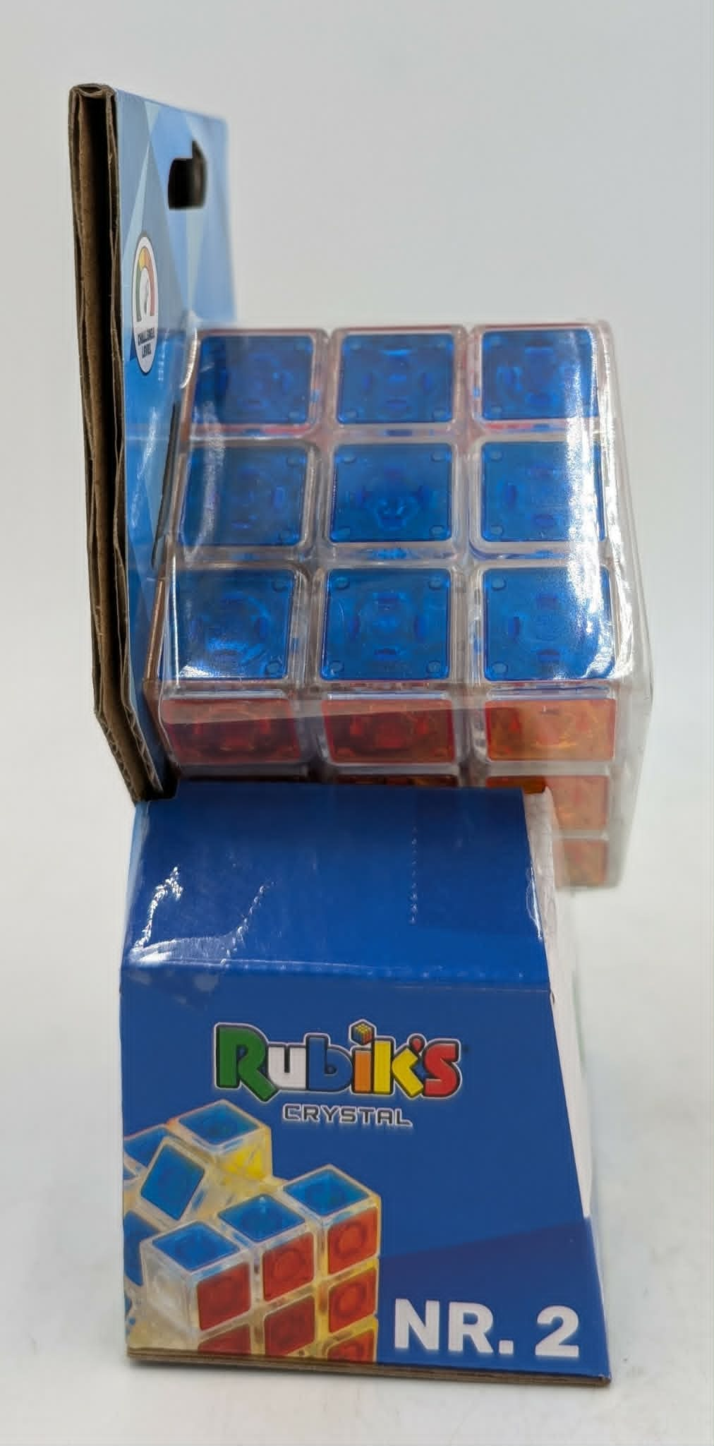 Ein klar verpackter Rubik's Crystal Würfel mit blauen und roten Quadraten, auf einer blauen Box mit der Aufschrift „Rubik's Crystal Nr. 2“.