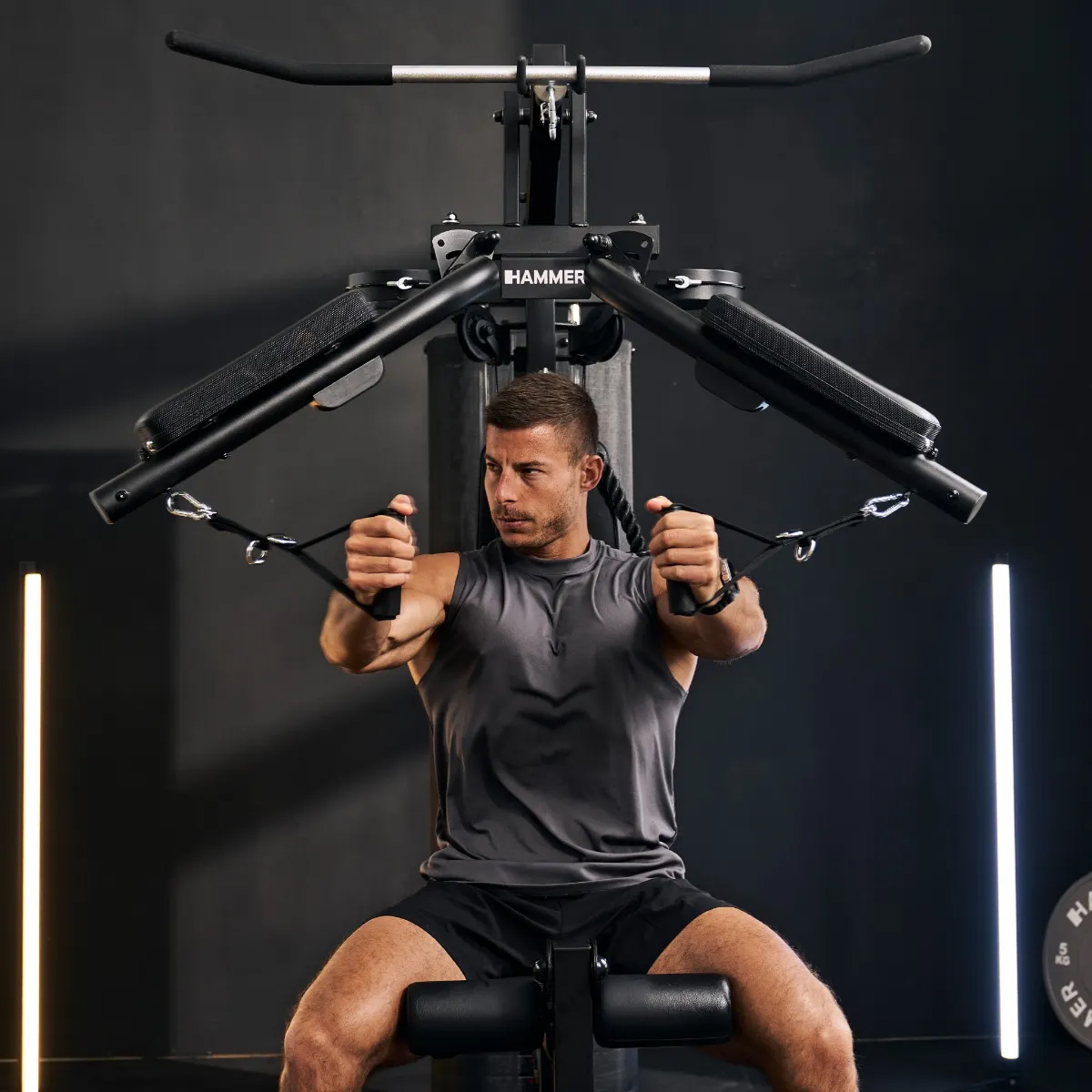 Ein Mann trainiert an einer schwarzen Hantelbank im Fitnessstudio.