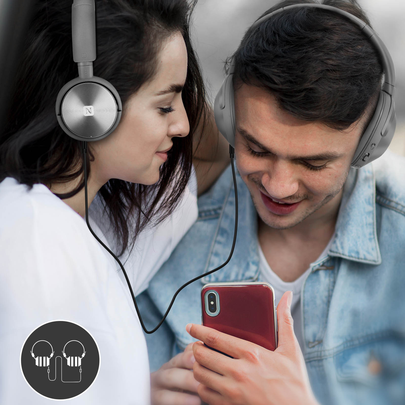 Two people share headphones and a phone. A woman on left, man on right.