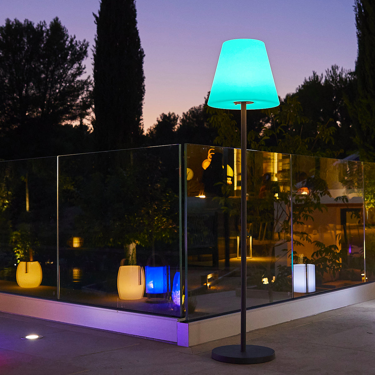 Un'area esterna illuminata al crepuscolo con una lampada da terra e diverse lanterne.