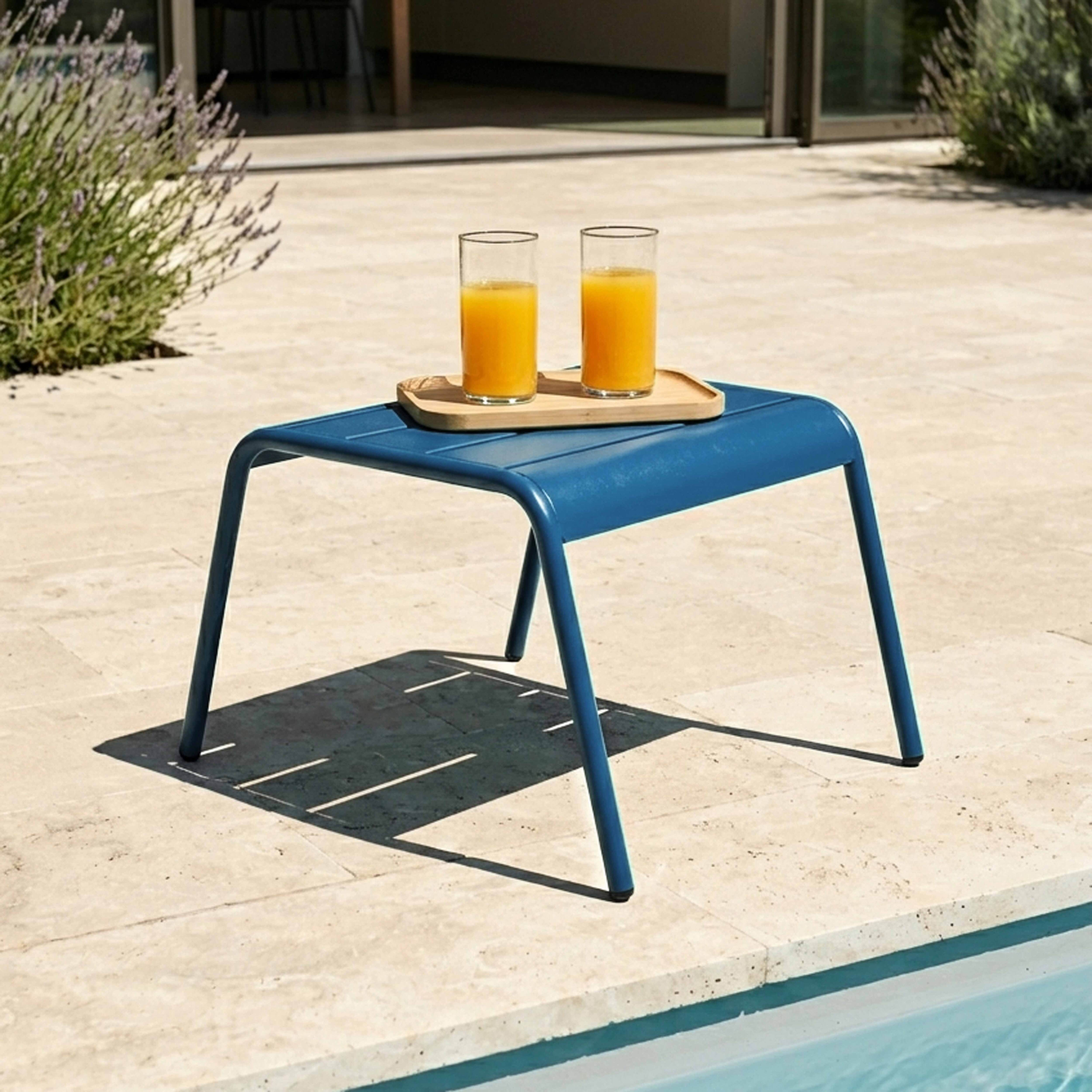 Ein blauer Beistelltisch mit zwei Gläsern Orangensaft auf einem Tablett.