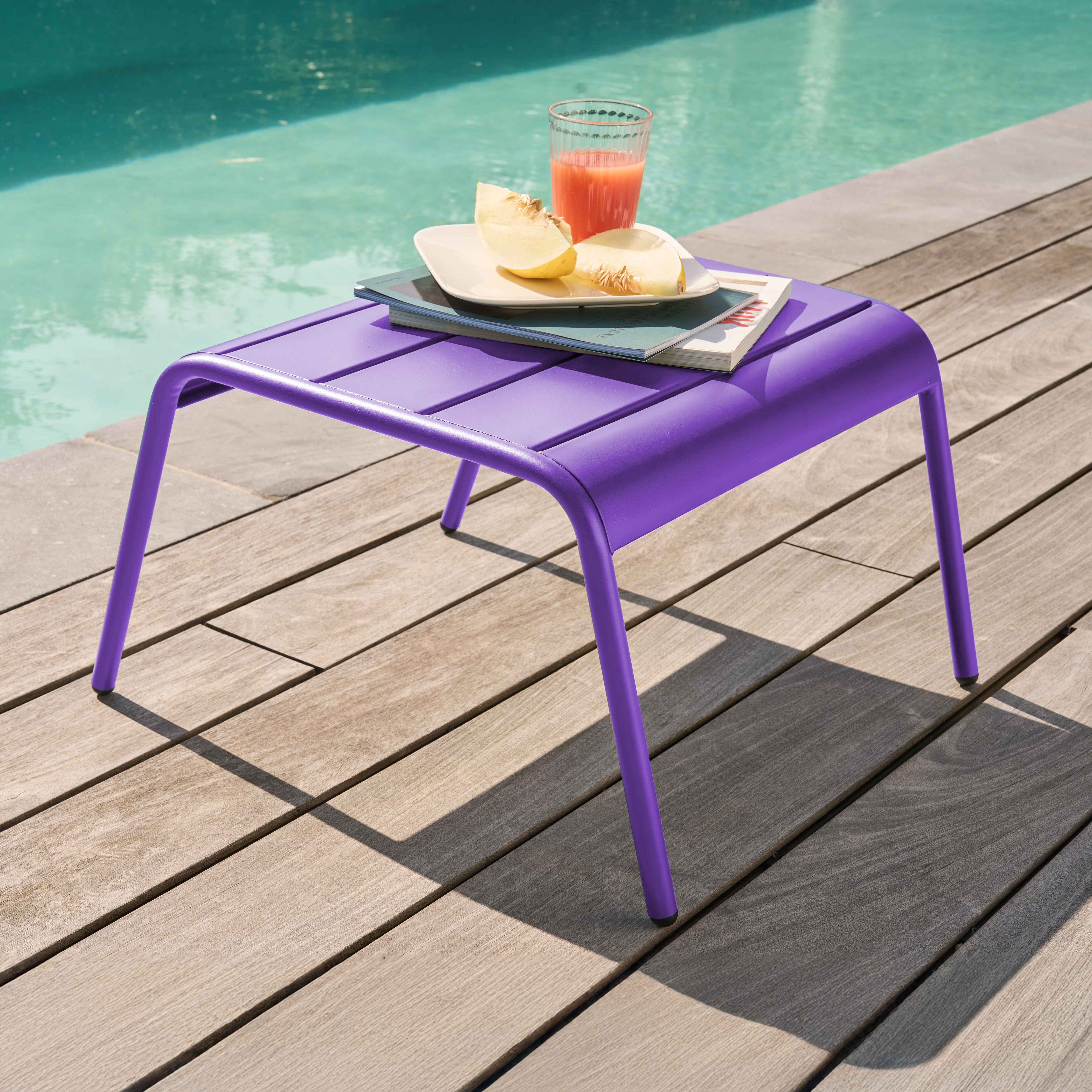 Ein violetter Tisch mit Saft und Melone am Pool auf Holzsteg.