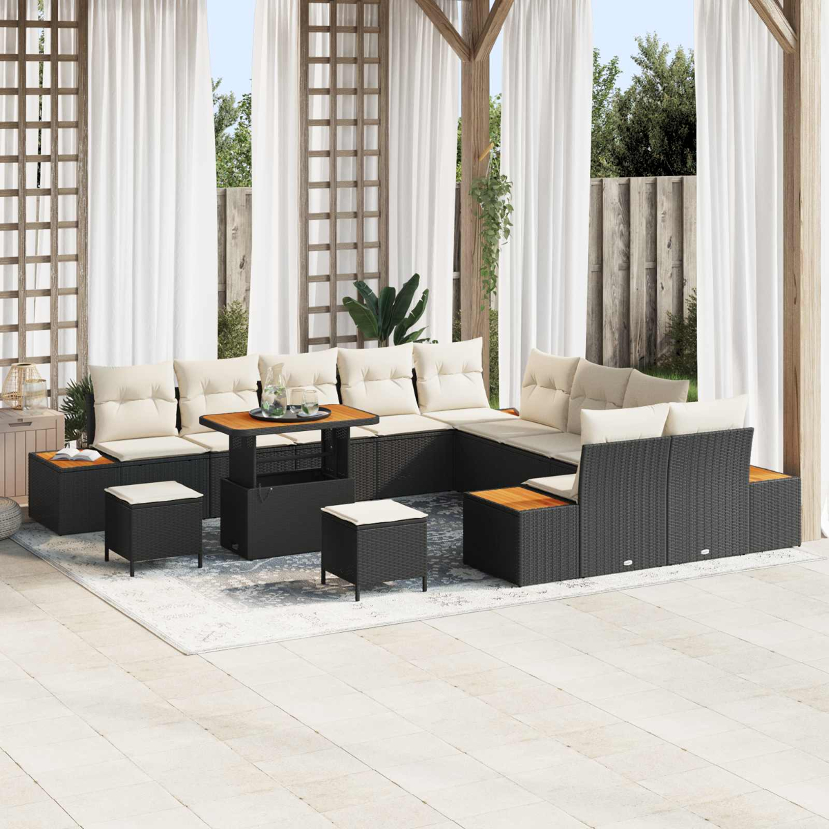 Ein dunkles Rattan-Lounge-Set mit cremefarbenen Kissen steht auf einer Terrasse.