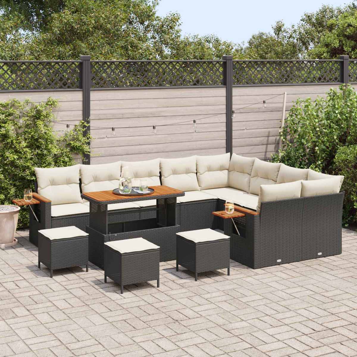 Dunkelgraue Lounge-Garnitur mit beigen Kissen und Holztisch auf einer gepflasterten Terrasse.