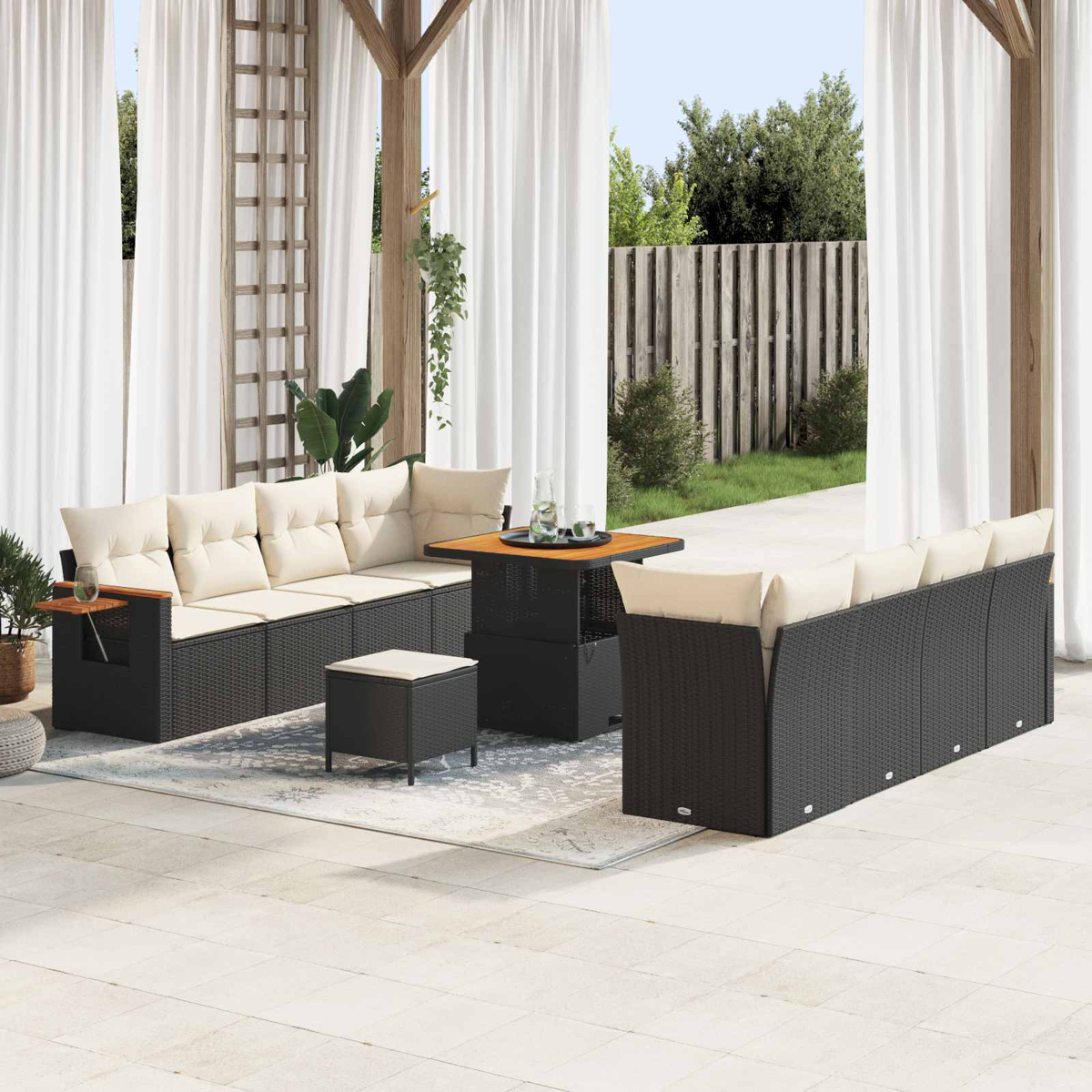 Dunkelbraunes Rattan-Sofa mit cremefarbenen Kissen und einem Tisch auf einer Terrasse.