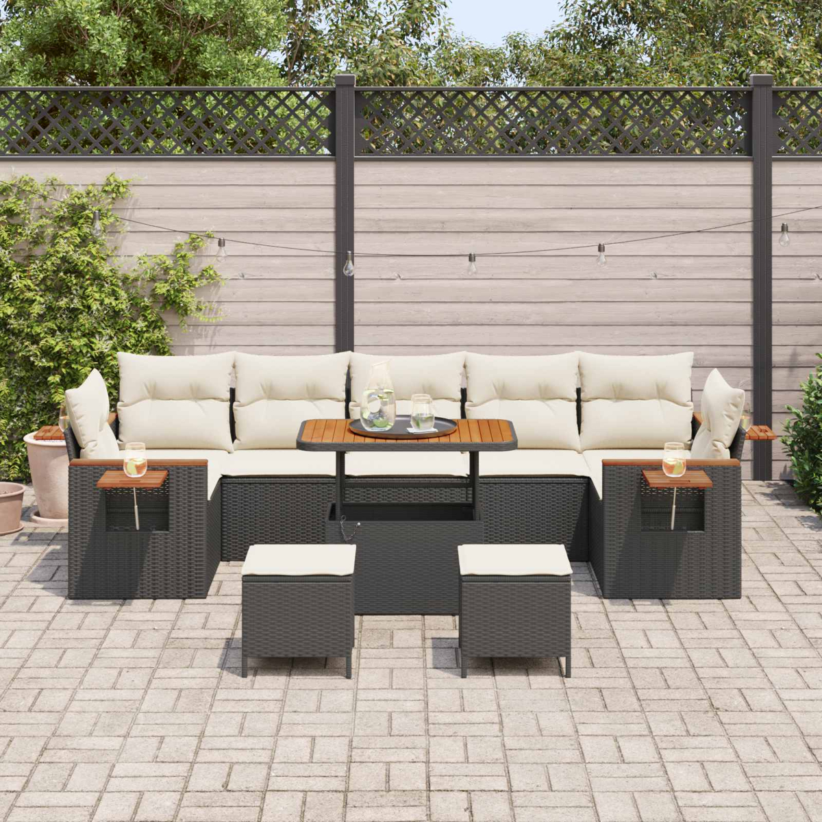 Ein dunkelgraues Rattan-Outdoor-Sofaset mit beigen Kissen auf einer gepflasterten Terrasse.